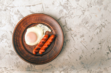Gluten free fried eggs. Breakfast on a clay plate of sausages and eggs. Keto diet close-up and copy space.