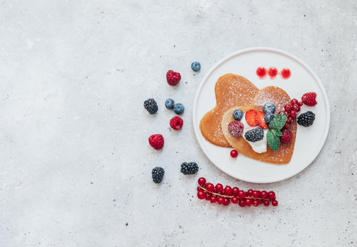 Homemade heart shaped pancakes with berries. Breakfast or brunch for Valentine's Day. Top view, Flat Lay