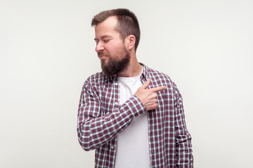 Get out! Portrait of angry bearded man in casual plaid shirt pointing finger to the side and turned away, looking irritated disappointed with your behavior. studio shot isolated on white background