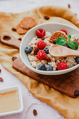 Oatmeal with berries in bowl on pink background