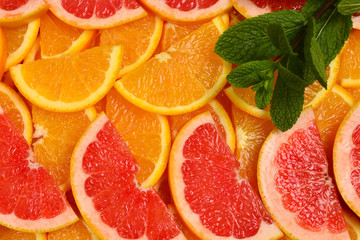 Slices of oranges and a grapefruits and mint as a background.