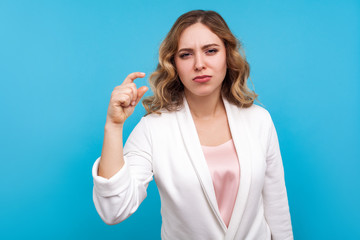 Some more please. Portrait of displeased woman with wavy hair in white jacket making a little bit...