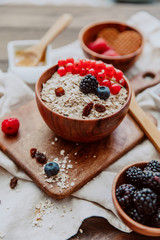 Oats in clay bowl with berries on wooden table