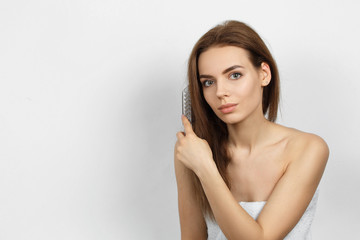 Obraz premium Beautiful woman in a towel combing hair.