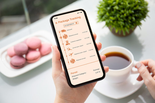female hand holding phone with app tracking delivery package