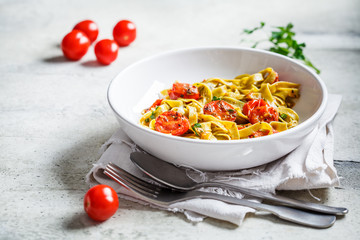 Green spinach pasta with tomatoes and herbs. Healthy vegan food concept.