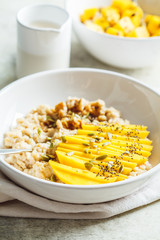 Oatmeal with mango and pumpkin seeds in white bowl. Healthy breakfast, vegan food.