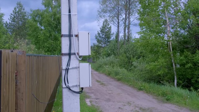 Electric shield on a street pole in the private sector, closeup view. Electric pole on a country road in the village near the fence. Modern equipment for wiring in country houses.
