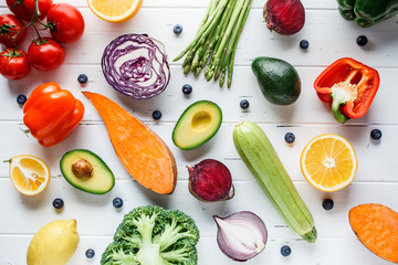 Rainbow colors vegetables and berries on white background, top view. Detox, vegan food, ingredients for juice and salad.