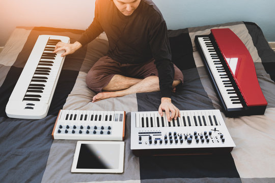 male asian young musician, songwriter enjoy playing music keyboards and piano on bed