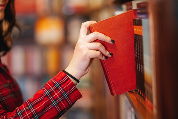 Intellectual Teenage girl choose books and pick them from a library or bookstore.