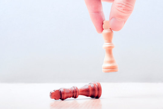 hand puts on the table a white piece of a chess kotol. on the table lies the defeated black king. business success concept.