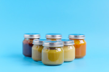 fruit and vegetable baby food in glass jars on a blue background, copy space healthy food for children