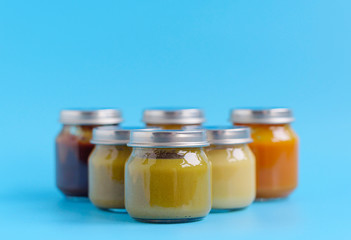 fruit and vegetable baby food in glass jars on a blue background, copy space healthy food for children