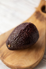 Avocado - dark whole avocado on board on wooden table. Selective focus