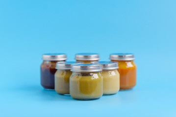 fruit and vegetable baby food in glass jars on a blue background, copy space healthy food for children
