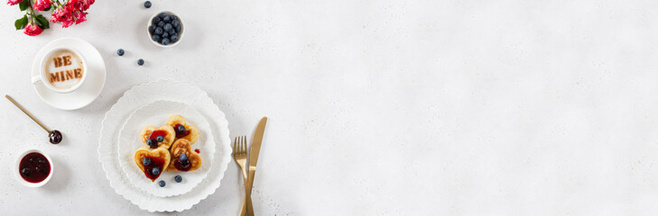 Heart shaped pancakes and a cup of coffee on a white background. Festive breakfast for Valentine's Day, sweet valentine. Cafe, restaurant menu banner. Copy space