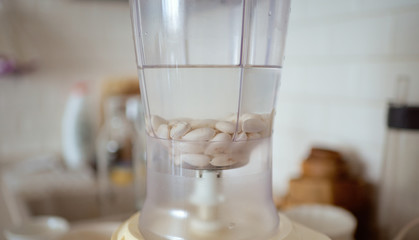 Blender and almonds soaked in water. Homemade healthy vegan milk.