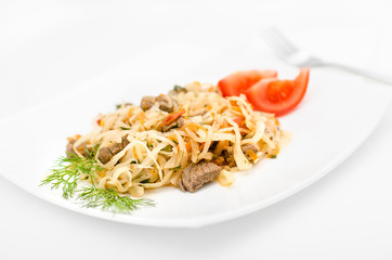 Stewed vegetables with meat: cabbage, onions, carrots and beef on a white plate on a white background