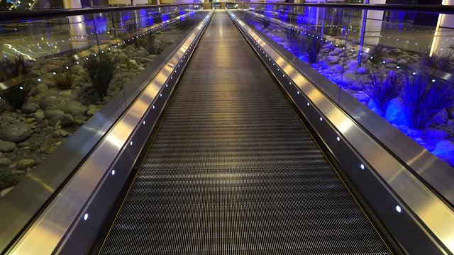 Moving walkway, moving sidewalk, moving pavement, travelator, horizontal escalator, moveator, or auto walk at an international airport terminal, in modern office centre