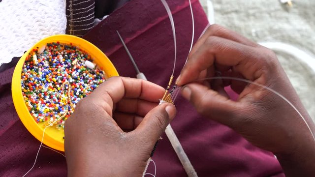 Making of handmade jewellery. Masai african women hands, top view, close up. Island of Zanzibar, Tanzania, East Africa
