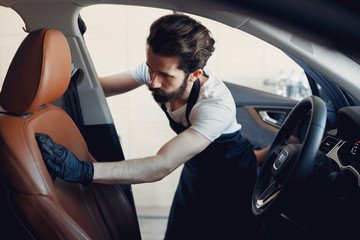 Man in a garage. Worker washing a car.