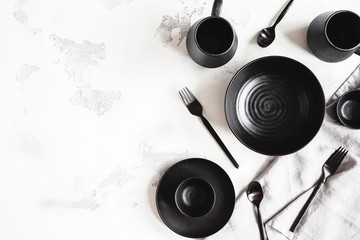 Black stylish tableware on white background. Flat lay, top view