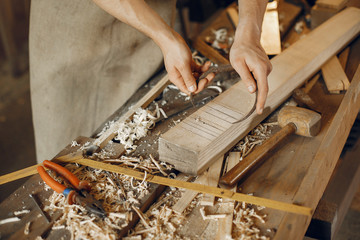 Man working with a wood. Carpenter in a white shirt
