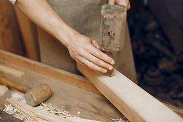 Man working with a wood. Carpenter in a white shirt