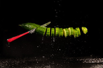 cucumber with splashing water or explosion flying in the air isolated on black background