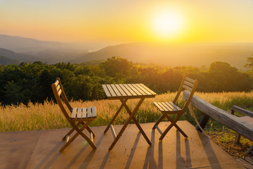 Empty wooden table and chairs on terrace. Beautiful seating with landscape mountains view while sunset.