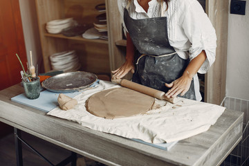 Woman in a pottery. Master make a dishes. Artist works with a clay