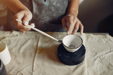 Fototapeta na wymiar Woman in a pottery. Master make a dishes. Artist works with a clay