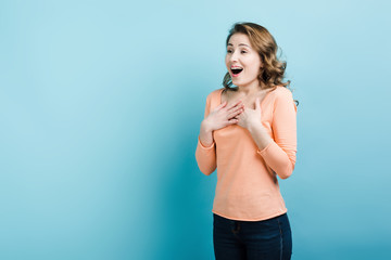 Naklejka premium Surprised young pretty girl looking away isolated on blue background