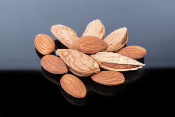 Peeled and unshelled almonds on a dark reflective surface