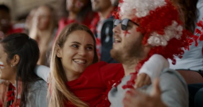 Happy English soccer supporters singing together in stadium. Group of fans with their arms around singing and swinging in fan zone during a game.