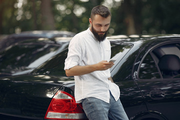 Handsome man in a white shirt. Businessman working with smartphone. Man standing near a car