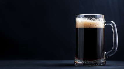 A mug of dark stout or porter beer on a black background with copy space