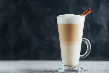 Glass of coffee latte with cinnamon on a concrete table