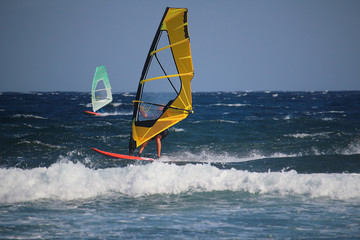 Windsurfer with yellow sail in turquoise water of the Atlantic Ocean