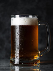A mug of cold light beer on a dark concrete background