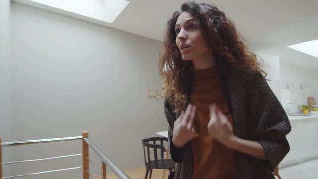 Medium tracking shot of beautiful Caucasian woman having furious argument with boyfriend while walking up stairs into apartment and taking off coats, verbally abusing and taunting each other