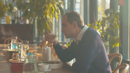 Man sit at a table in cafe and eat salad