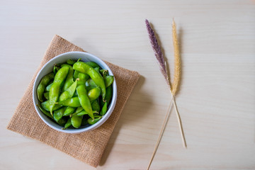 Green Japanese Soybean in white bowl on table wood and Dried flower