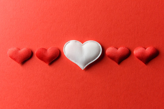 Red and white textile hearts on red paper. Valentines day background, creative texture and love concept