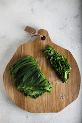 Top view of juicy spinach on wooden board on the marble table. Preparation for making organic salad,copy space