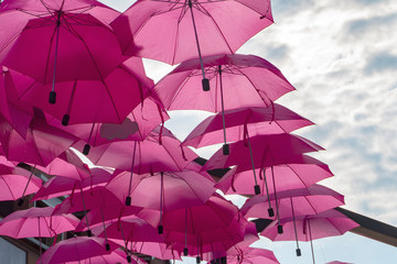 Fototapeta na wymiar Street art installation of bright pink umbrellas