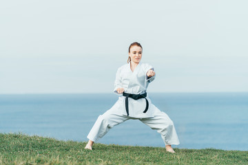 Young female redhead karate fighter hitting a left punch