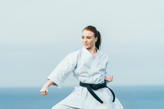 Young redhead female karate athlete training outdoor.