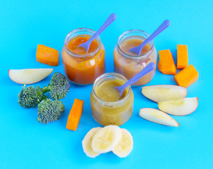 fruit and vegetable baby food in glass jars on a blue background, copy space healthy food for children